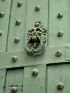 aldaba verde con cara de león y puerta verde