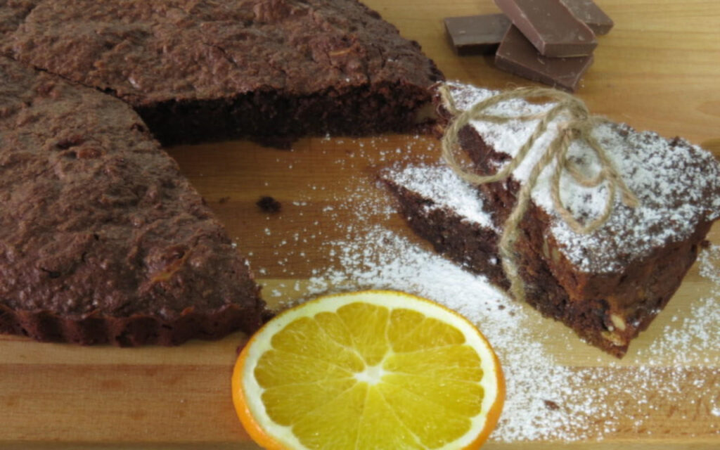 Brownie cortado con azúcar glas y una rodaja de naranja