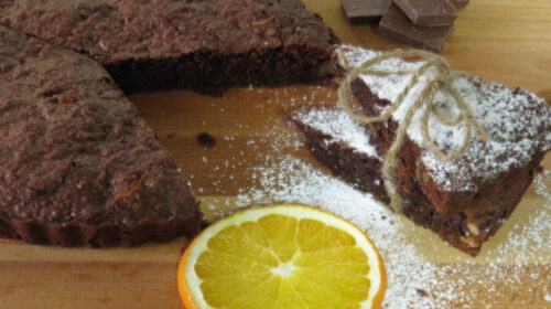 Brownie cortado con azúcar glas y una rodaja de naranja
